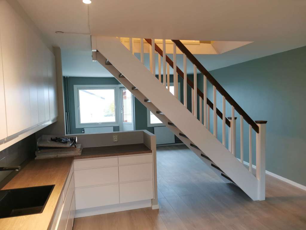 Image of a renovated kitchen with white cabinets and a stair