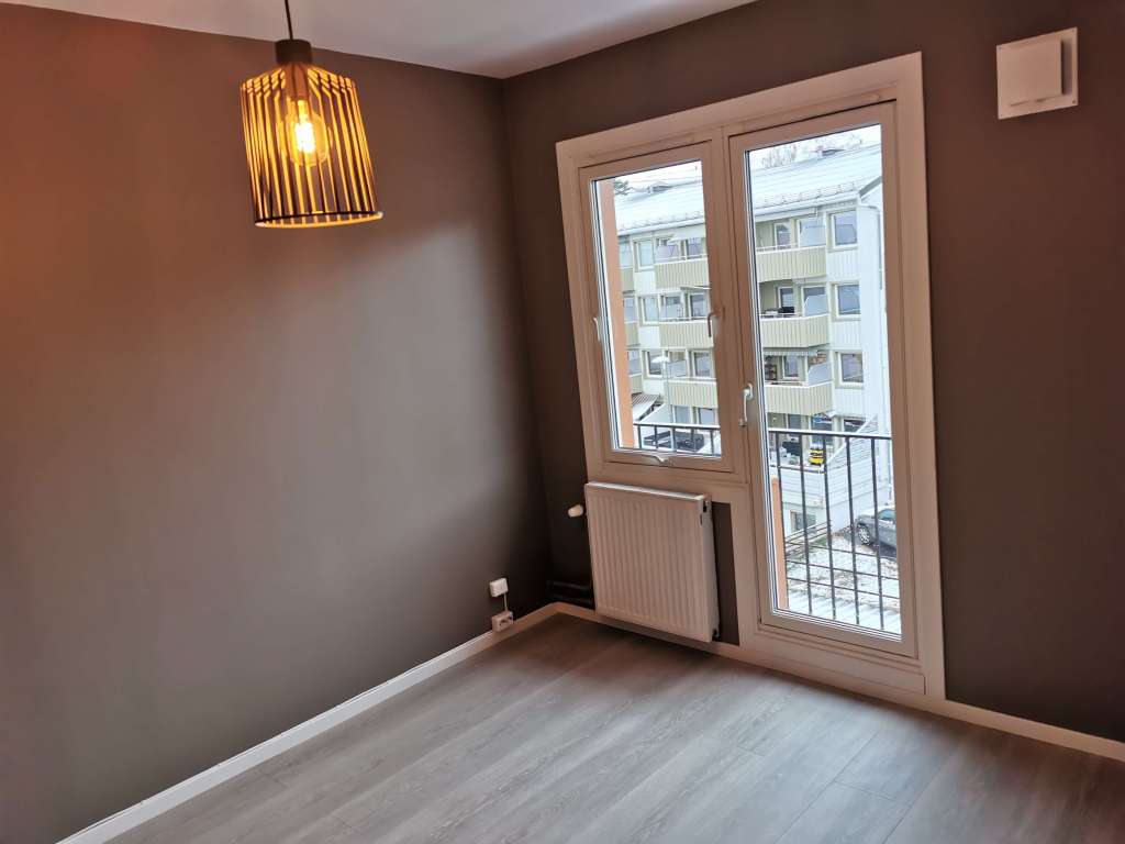 Image of a renovated room with grey walls, a window and a door