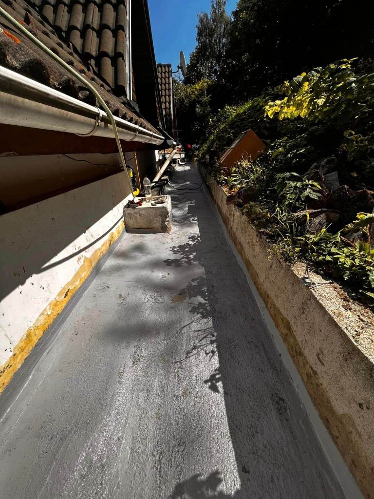 Image of a waterproofing operationbehind a house with liquid membrane